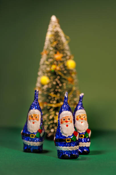 A small red Santa Claus ornament is delicately hanging from a pine tree branch. The scene captures the festive spirit of the winter season with the vibrant green foliage and cheerful decoration.