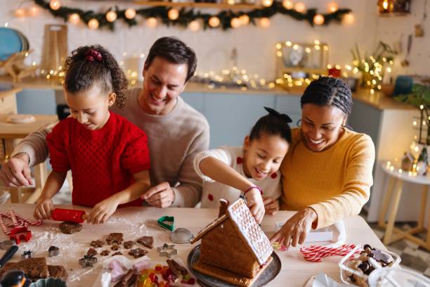 istock Parents and their daughters decorating a gingerbread house 2185754519