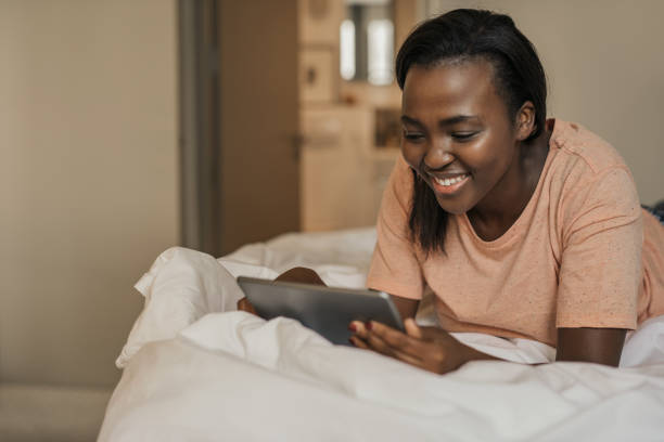 istock Smiling African American woman lying in bed using a tablet 2185756791