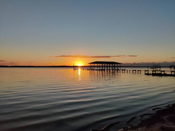 istock Sunset over calm lake with pier silhouette 2185762417