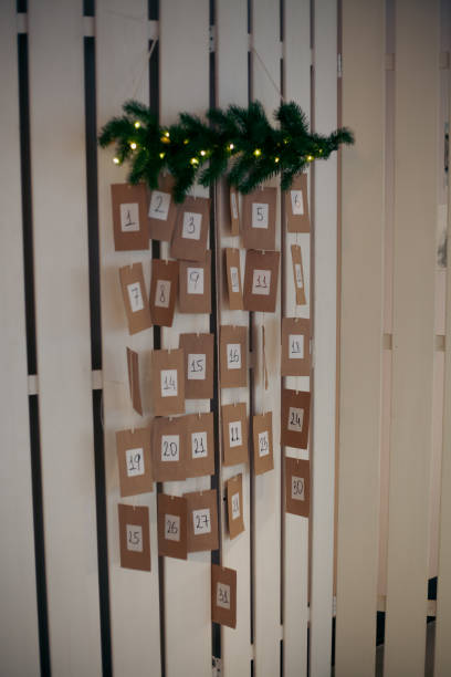 istock A charming advent calendar is displayed on a white wooden wall. It features numbered packets from 1 to 24, adorned with festive greenery and soft lights for a cozy holiday atmosphere 2185764561