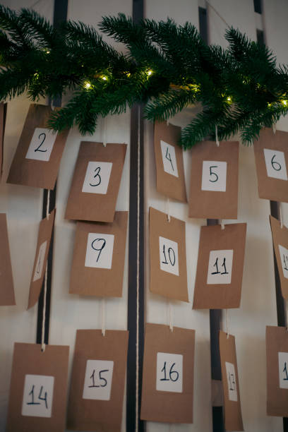 istock A countdown calendar showcasing numbered brown cards hangs on a wall, adorned with a pine garland and soft lights, creating a cozy holiday atmosphere 2185764588