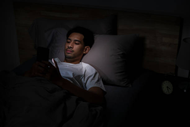istock Depressed Young Asian man lying in bed using smartphone late at night 2185764673