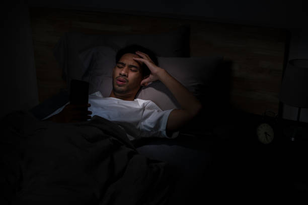 istock Depressed Young Asian man lying in bed using smartphone late at night 2185764689