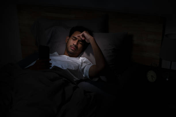 istock Depressed Young Asian man lying in bed using smartphone late at night 2185764690