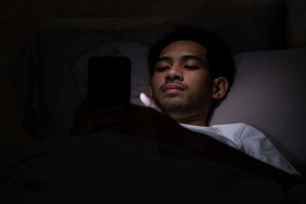 istock Depressed Young Asian man lying in bed using smartphone late at night 2185764734