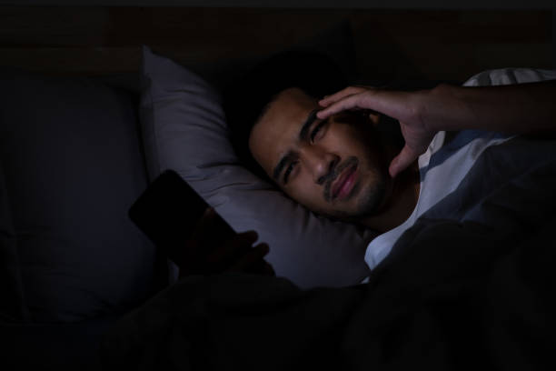 istock Depressed Young Asian man lying in bed using smartphone late at night 2185764762