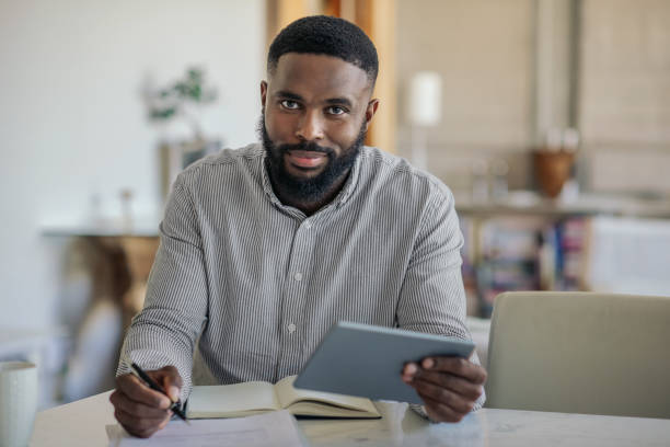 istock Smiling African American man using a digital tablet at home 2185768188