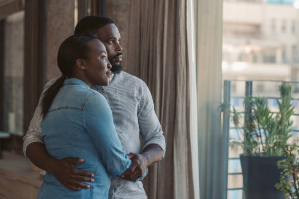 istock Affectionate young African American couple looking out of a window 2185769593
