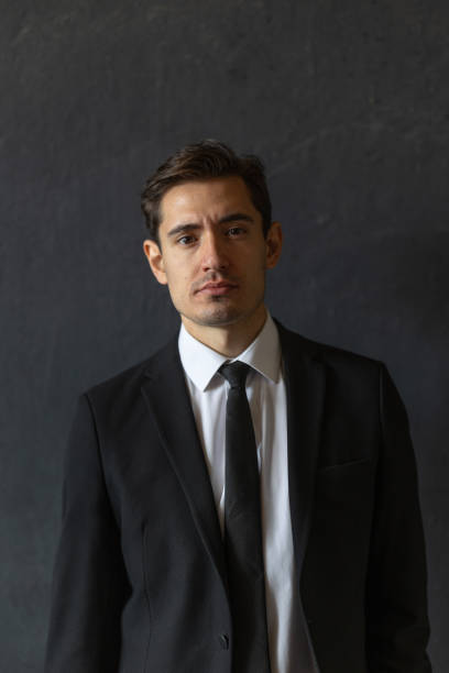 istock Confident Young Professional Posing in Black Suit Against Dark Background 2185771063