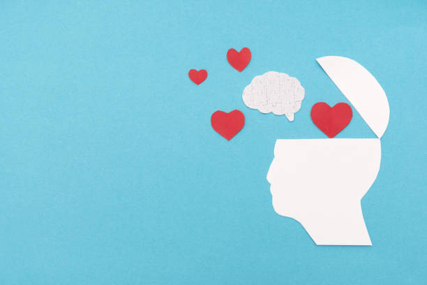 istock Silhouette of an open human head with a brain puzzle and red hearts floating, symbolizing the balance between logic and emotions on a blue background 2185772409