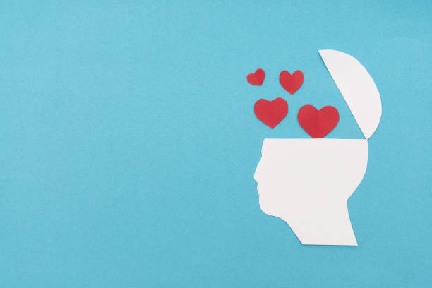 istock Silhouette of an open human white head with red hearts floating out symbolizing emotions and mental health on a blue background 2185772413