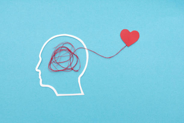 istock Silhouette of head with tangled red thread connecting to heart symbolizing mental and emotional health on blue background 2185772430