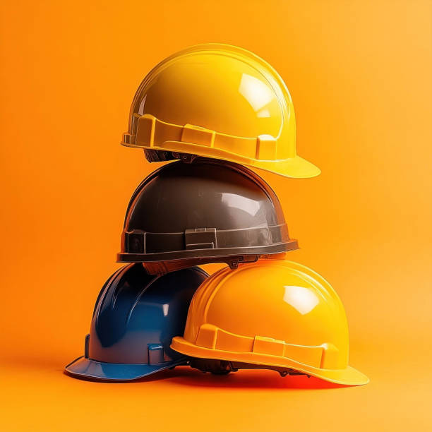 Minimalist composition featuring colorful hard hats stacked against a striking orange backdrop, ideal for construction, safety, and industrial themes.