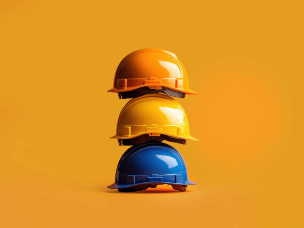 istock Minimalist composition featuring colorful hard hats stacked against a striking orange backdrop, ideal for construction, safety, and industrial themes. 2185773302