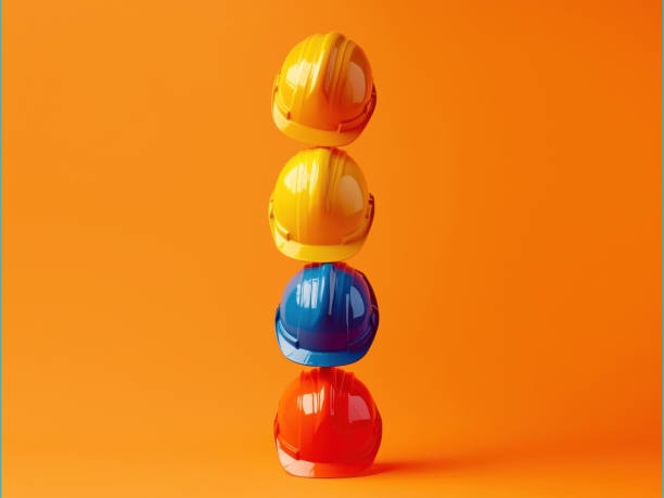 istock Minimalist composition featuring colorful hard hats stacked against a striking orange backdrop, ideal for construction, safety, and industrial themes. 2185773328