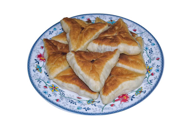Triangular fried pies with chicken meat and onions on a platter isolate on a white background.