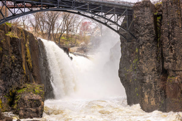 istock Powerful waterfall cascading between rocky cliffs with an iron bridge overhead in Paterson, New Jersey. USA. 2185782299