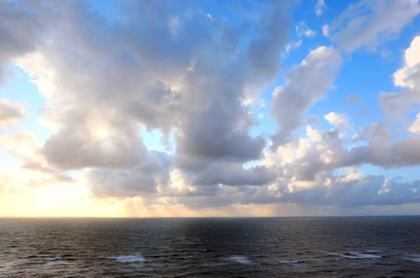 sunlight filtering through clouds over a calm sea in a vast peaceful landscape with reflections on the water and a serene atmosphere