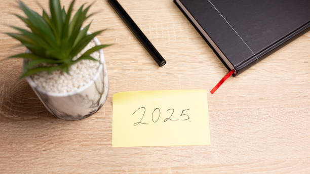istock Desk with agenda, pen and sticky note showing 2025, planning and organization concept 2185785429