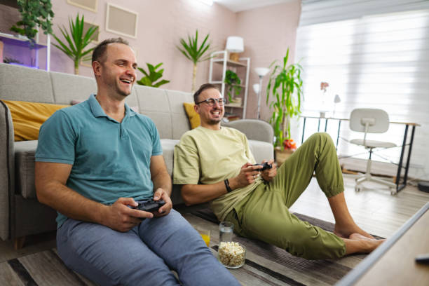 istock Two smiling men playing video games at home 2185785928