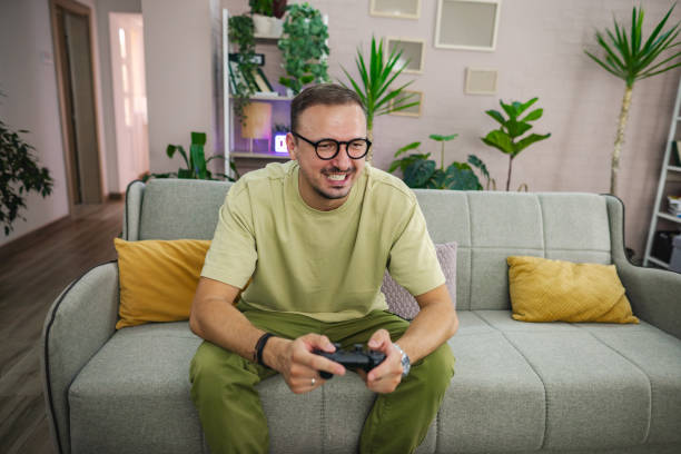 istock Excited man playing videogames on the couch at home 2185785968