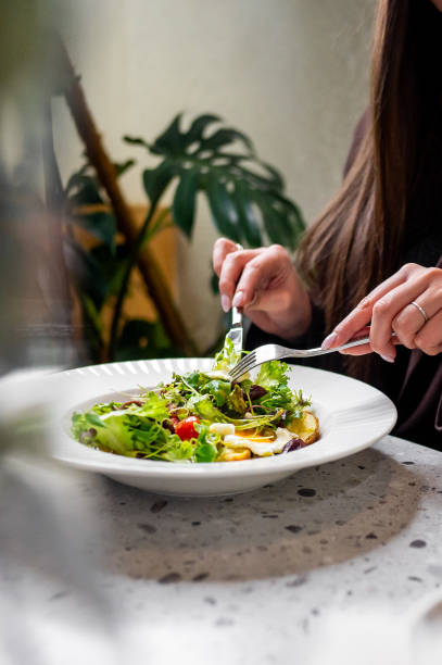 istock A person enjoys a fresh salad with various greens and vegetables, emphasizing a healthy lifestyle. The vibrant colors and fresh ingredients highlight the appeal of nutritious eating 2185786963