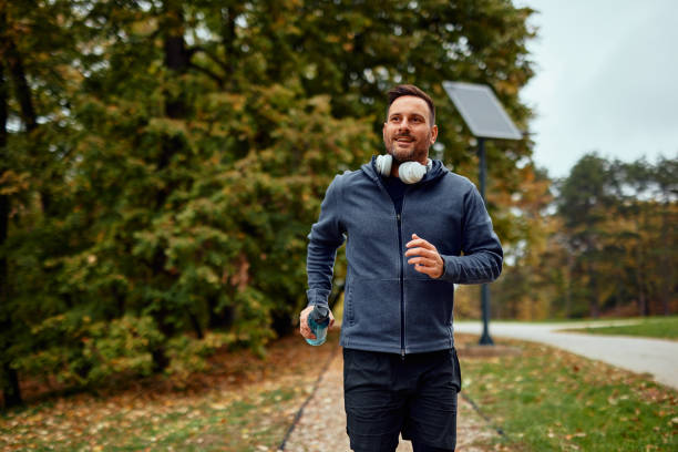 istock Man Jogging with Headphones in Scenic Park Setting 2185790674