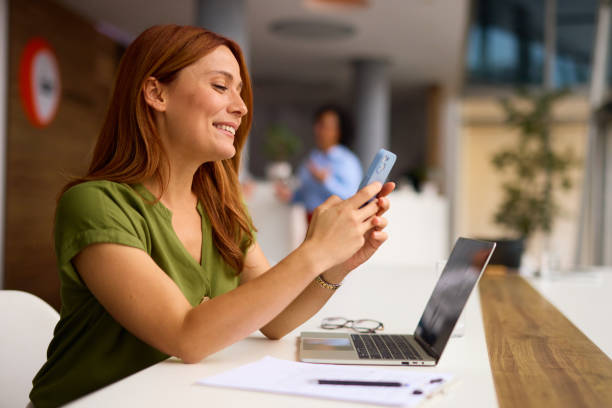 istock Confident Woman in Office Using Smartphone and Smiling 2185791301