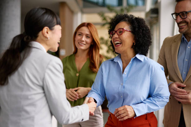 diverse business colleagues shaking hands in a modern office - connexion photos et images de collection