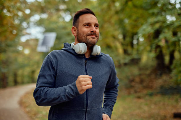istock Man Jogging Through a Scenic Forest Trail in Autumn 2185792043
