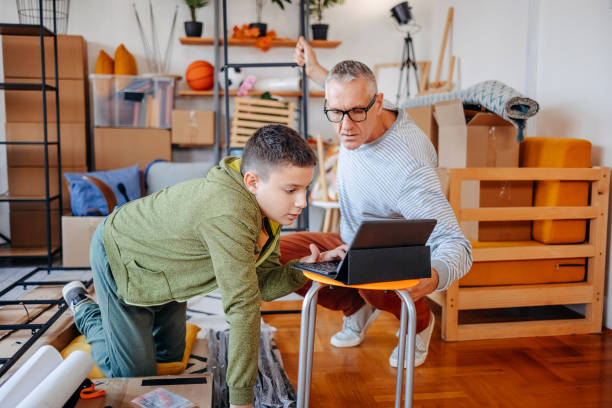 istock Father and son moving in new home and assembling shelf together with digital tablet support 2185795123