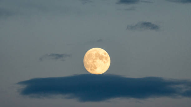 A close-up of a full moon resting on a cloud