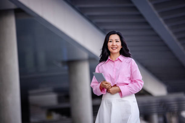istock Stylish woman holding tablet under sleek architecture 2185810912