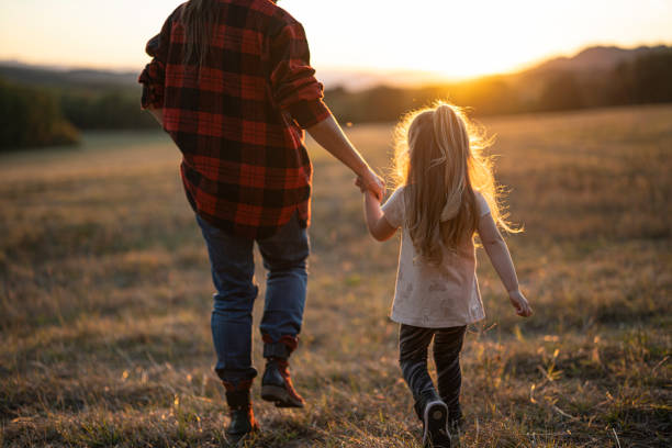 istock Nature Hike. Mom and Child Holding Hands and Walking at Sunset 2185825087
