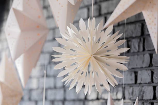 Beautifully crafted paper decorations dangle from the ceiling, enhancing the cozy atmosphere of the indoor space with their unique shapes and elegant white color.
