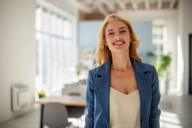 istock Smiling woman in blue jacket standing in bright room 2185830409