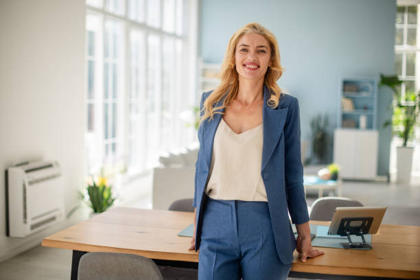 istock Smiling woman in office setting wearing blue business suit. 2185830441