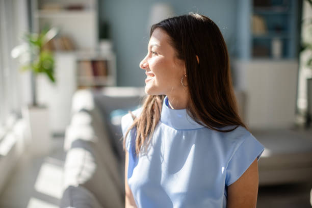 Smiling woman in soft lighting by large window inside