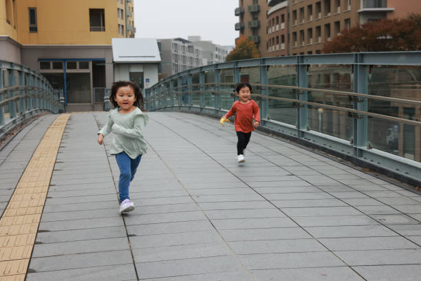 A beautiful moment of two kids running energetically by a water fountain in a park, embodying the joy and spontaneity of childhood laughter in a lively summer day scene.