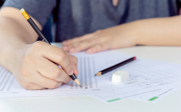istock Students hand holding pencil writing selected choice on answer sheets and Mathematics question sheets. students testing doing examination. school exam 2185846165