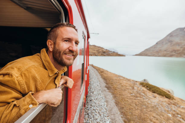 istock Man Enjoying Scenic Train Journey by an alpine lake 2185848983