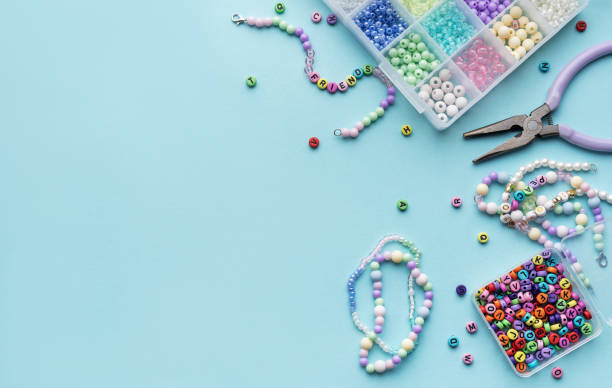 istock Colorful assortment of beads and jewelry-making tools on a blue surface with completed bracelets 2185860023