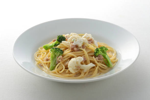 A plate of pasta with root vegetables, leafy vegetables, and beans