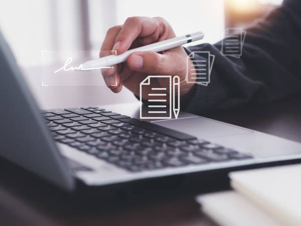 istock Businessman signing documents through interface laptop screen using stylus pen on office desk at home. Paperless office. 2185862820