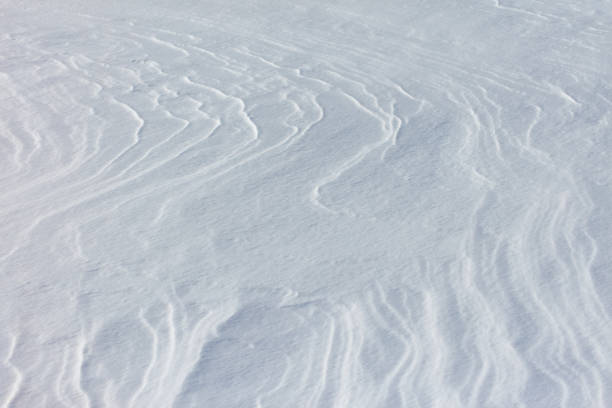 Close-up of snow texture on a ski slope with skis and foot imprints.
