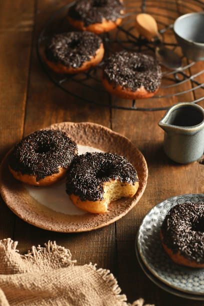 istock Donuts (donat) with chocolate topping on wooden background accompanied by a rustic napkin and plate. 2185863063