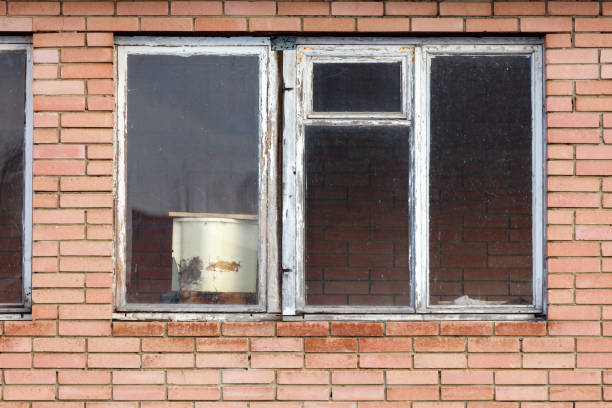 A window with a white bucket in front of it. The bucket is empty and has a few scratches on it. Scene is somewhat sad and lonely
