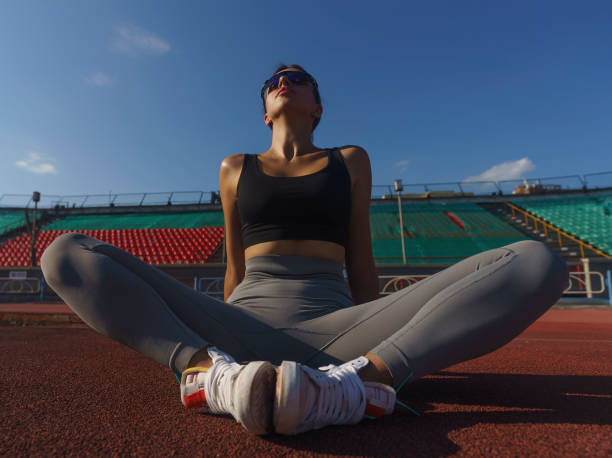 the athlete is sitting on the stadium treadmill, taking a break from training, playing sports on a summer day
