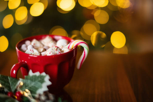 istock Hot chocolate mug with marshmallow and candy cane over Christmas tree background 2185866154